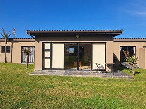 A modern house with a patio, large sliding glass doors, and a small garden area. - Umbono Private Lodge (Alexandria)