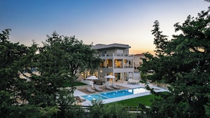 A modern two-story building with a swimming pool, surrounded by lush greenery. - Heated pool, outdoor playground, convenient location close to the beach and town (Rethymno)
