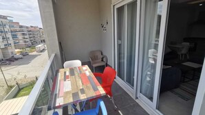 Ein Balkon mit Tisch und Stühlen, eine Schiebeglastür und Blick auf die umliegenden Gebäude.