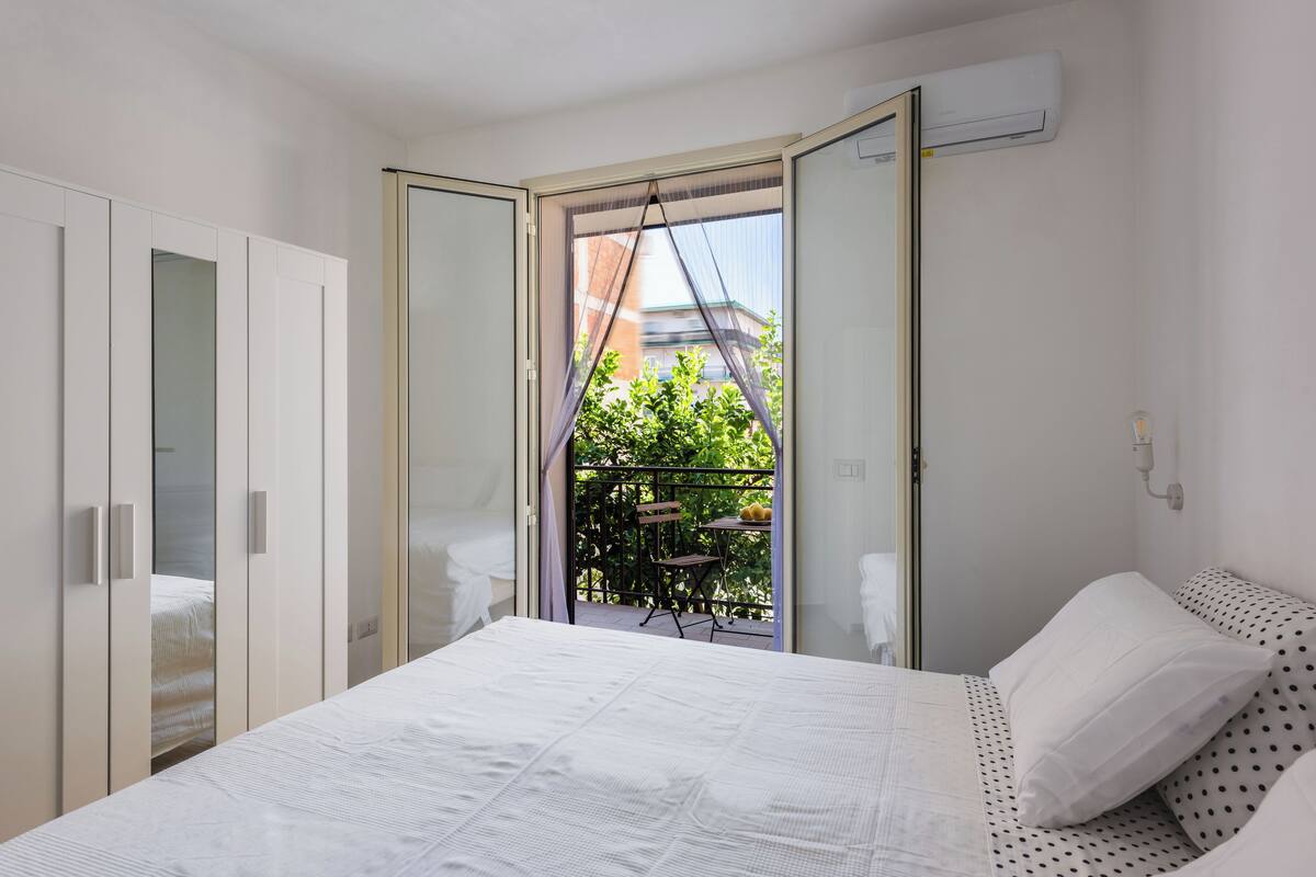 Ein Schlafzimmer mit Bett, Schrank und einem Balkon mit Tisch und Stühlen.
