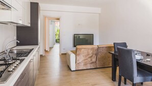 A modern kitchen with a built-in stove, a sink, and a dining area with a sofa and chairs. - Casa Lilium a Floridia by Wonderful Italy (Floridia)