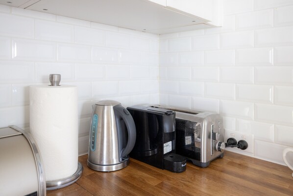 Eine Küche mit Kaffeemaschine, Toaster und Wasserkocher auf einer Holzauslage.