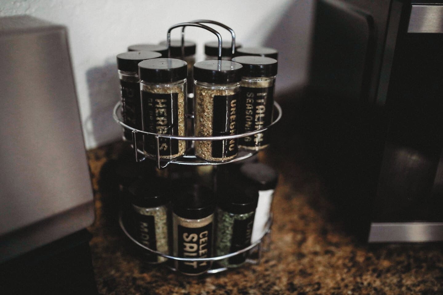 Un estante de metal con varias botellas etiquetadas 'CELI SAI' sobre una encimera de cocina.