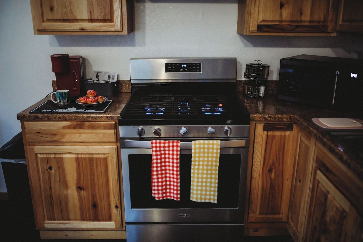 A kitchen with wooden cabinets, a stainless steel stove, and two ovens.