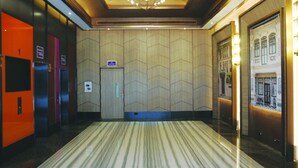 Un hall d’hôtel doté d’un tapis à motifs, d’un lustre et d’une grande fresque murale.