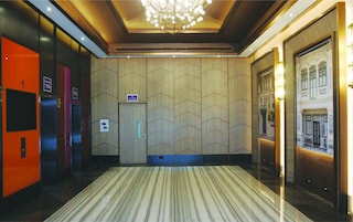 Un vestíbulo de hotel con alfombra estampada, un candelabro y un mural grande en la pared.