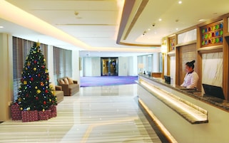 Un hall de hotel con un árbol de Navidad, una recepción y una zona de estar.