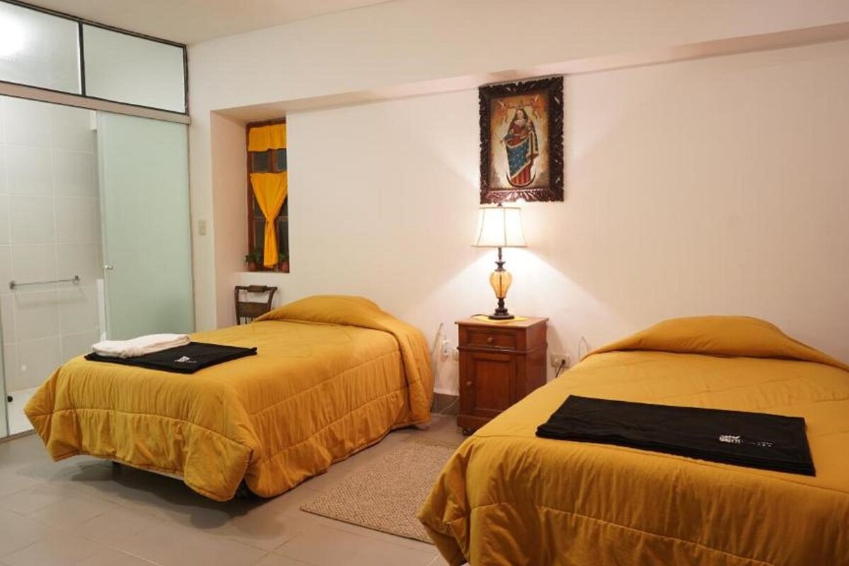 A hotel room with two beds, a nightstand, a lamp, a painting, and a wardrobe.