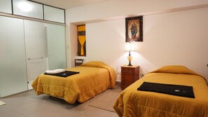A hotel room with two beds, a nightstand, a lamp, a painting, and a wardrobe. - Museo Hacienda Cayara (POTOSI)