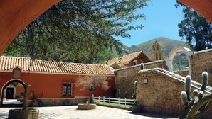 Un patio con una fuente, plantas de cactus y un edificio con techo de tejas.