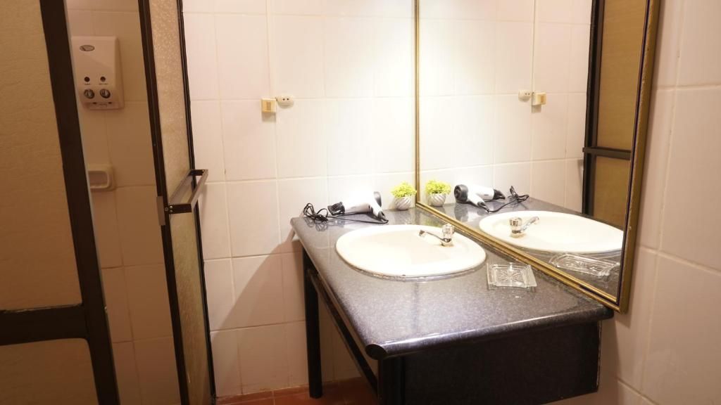 Un baño con dos lavamanos, un espejo y un perchero para toallas.