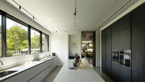 A modern kitchen with a large island, dark cabinetry, and a view of the outdoors.
