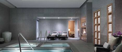 Zona de spa con piscina, sillas de descanso y una recepción.