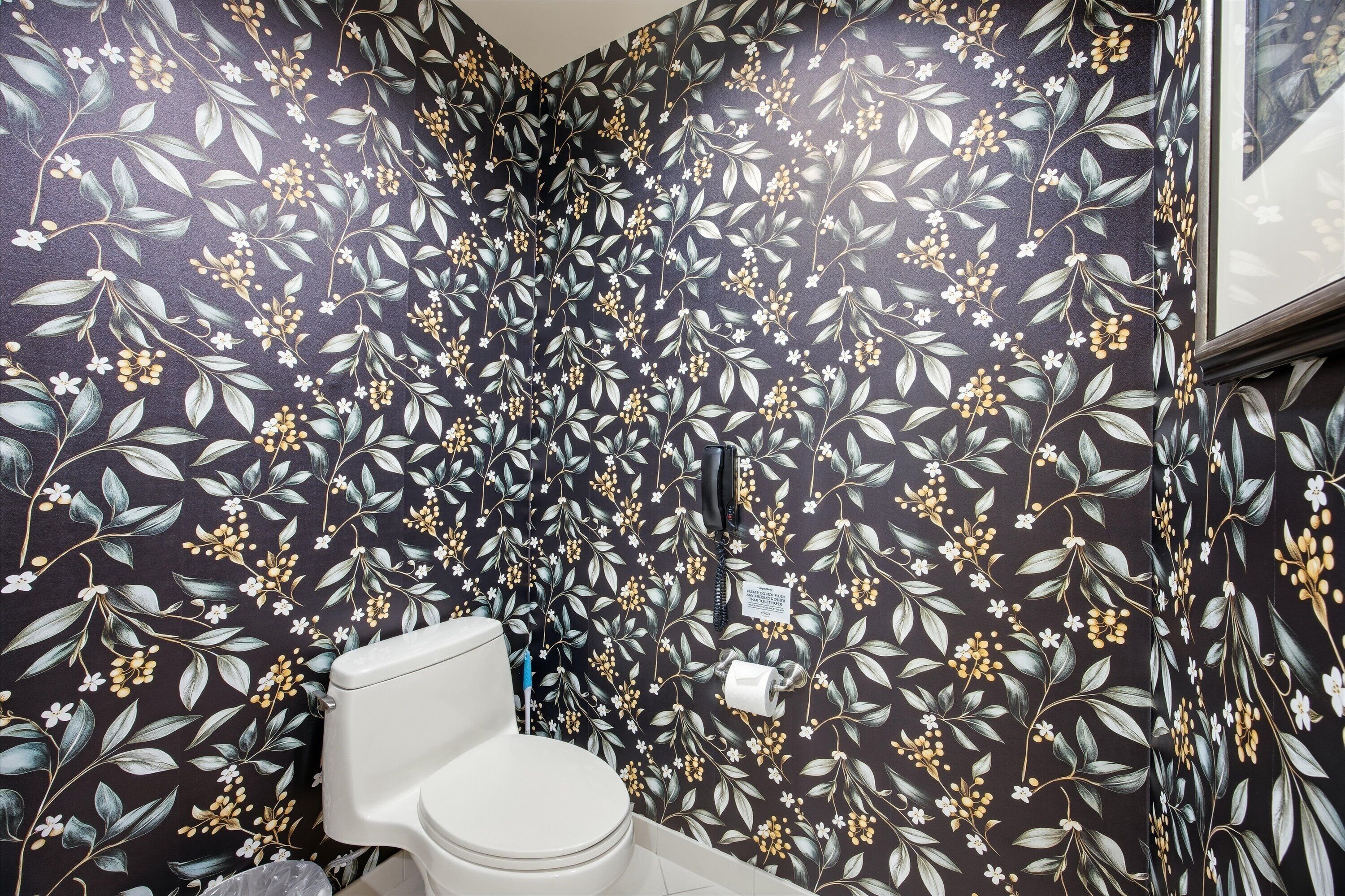 A bathroom with a floral wallpaper pattern, a toilet, and a towel rack.
