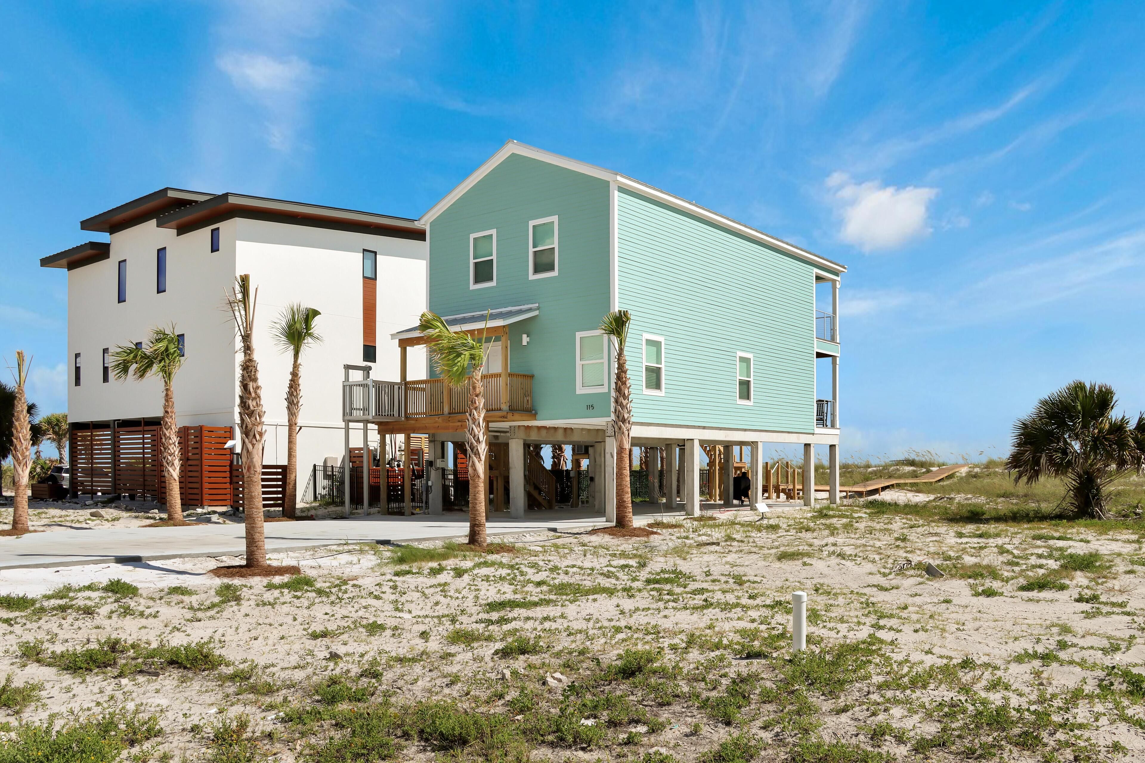 A two-story beachfront property with a covered patio and a balcony.