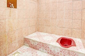 A bathroom with a toilet, tiled walls, and a patterned floor. - Hotel O Guest House Mustika Syariah Near alun alun kota purwokerto (Purwokerto)