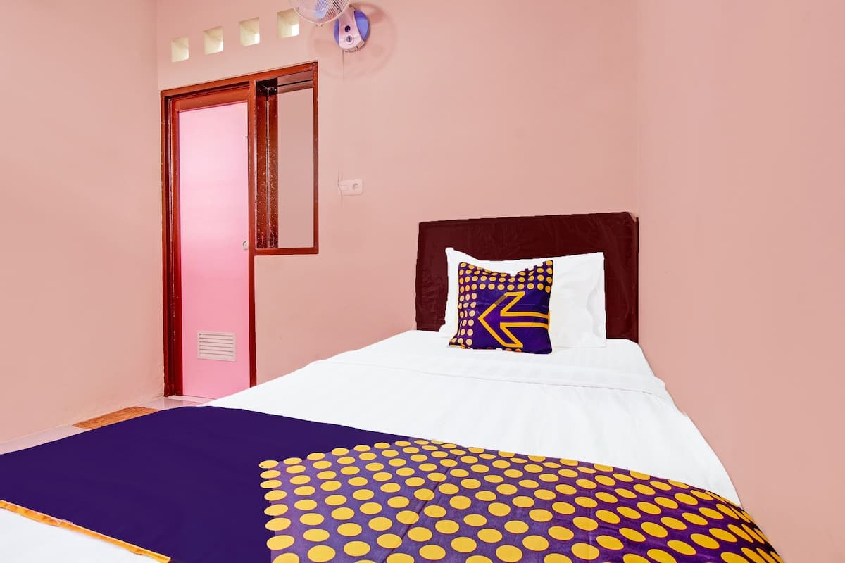 A bedroom with a bed, a wooden headboard, a purple and yellow polka dot blanket, and a pillow with a geometric pattern.