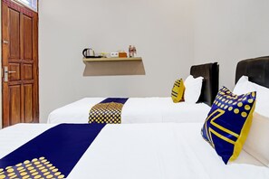 A hotel room with a bed, a bedside table with a kettle, a bottle, and a cup. - Hotel O Guest House Mustika Syariah Near alun alun kota purwokerto (Purwokerto)