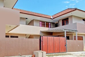 A multi-story residential building with a tiled roof, a gated entrance, and a covered outdoor area. - Hotel O Guest House Mustika Syariah Near alun alun kota purwokerto (Purwokerto)