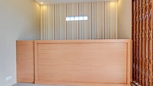Een kamer met een houten receptiebalie, een verticaal gestreept wand en een houten scheidingswand met een lattenstructuur.
