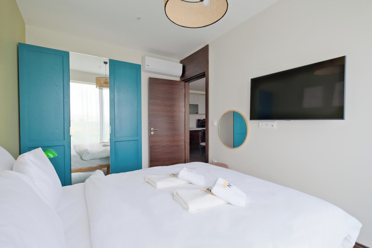 A hotel room with a bed, a TV, a mirror, and a wardrobe.