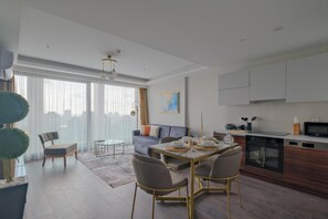A modern living room with a dining area, a sofa, and a kitchen with a built-in oven.