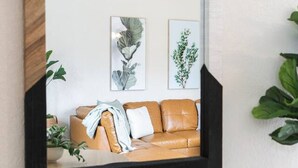A room with a large mirror, a brown leather sofa, and two framed botanical prints on the wall. - Sleeps 7{SPACIOUS}Pets Welcome! (Sheboygan)