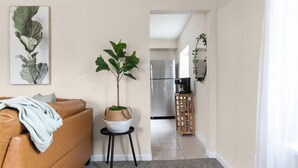 A living room with a brown leather sofa, a small white table with a plant, and a framed botanical print on the wall. - Sleeps 7{SPACIOUS}Pets Welcome! (Sheboygan)