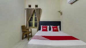 A hotel room with a bed, a chair, a window with curtains, and an air conditioning unit. - OYO 91187 Palanta Homestay Syariah (Pekanbaru)