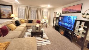 Ein Wohnzimmer mit einer Sofagarnitur, einem Couchtisch, einem Fernseher und einem Kamin.