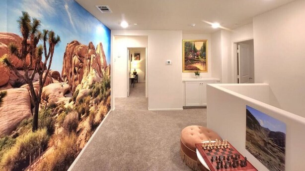 Ein Zimmer mit einer Wüstenmalerei, einem Schachbrett und einer Tür zu einem anderen Raum.