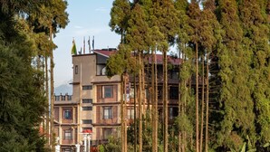 Un immeuble à plusieurs étages, dont la façade est un mélange de briques et de béton, entouré de grands arbres.