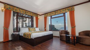 Une chambre spacieuse avec un grand lit, deux fauteuils et une vue sur l’extérieur.