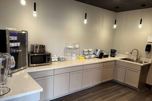 A modern kitchen with a refrigerator, microwave, toaster, and coffee maker. - Ramada By Wyndham Studio Suites Dothan (Dothan)