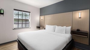 Un dormitorio moderno con una cama grande, una ventana, una mesita de noche e iluminación integrada en la pared.