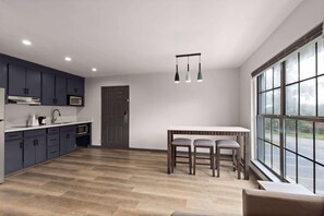 A modern kitchen with dark cabinets, a white countertop, and a dining area with a table and chairs.