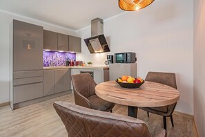 Una cocina moderna con microondas integrado, cafetera y frutero sobre la mesa de comedor.