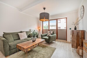 Un salón con un sofá verde, una mesa de centro de madera y una lámpara colgante.
