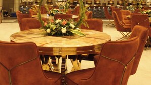 Comedor con mesas redondas, sillas tapizadas en rojo y un arreglo floral central.