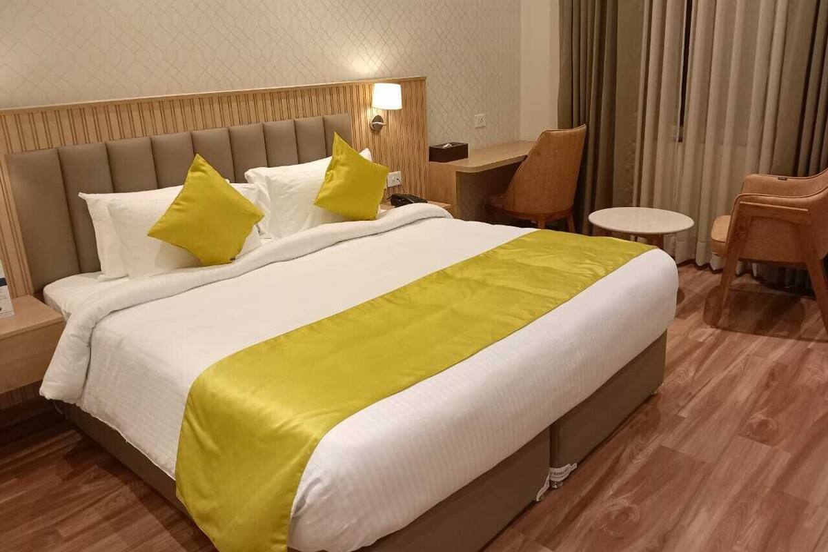 Quarto de hotel com uma cama grande, mesa de cabeceira, escrivaninha e uma cadeira.