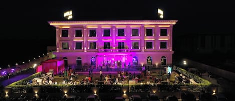 A large, multi-story building with a central stage and seating area, surrounded by a landscaped garden.