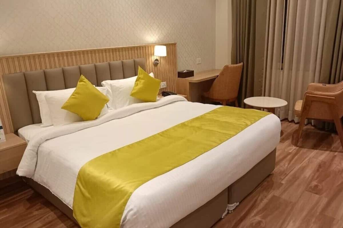 Quarto de hotel com uma cama grande, duas mesas de cabeceira, uma escrivaninha e uma cadeira.