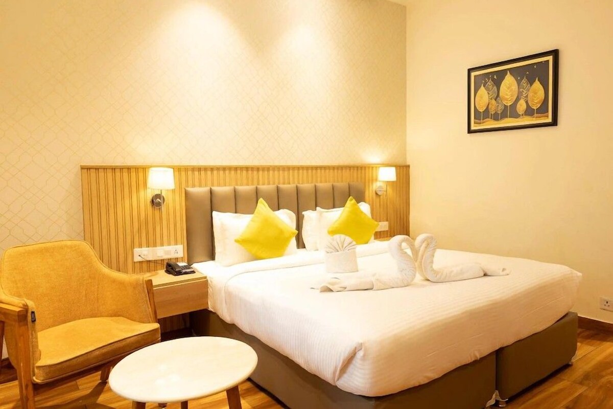 A hotel room with a bed, a chair, a small table, and a wall-mounted picture.