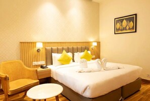 A hotel room with a bed, a chair, a small table, and a wall-mounted picture. - Antilia By Zion (Sonepat)