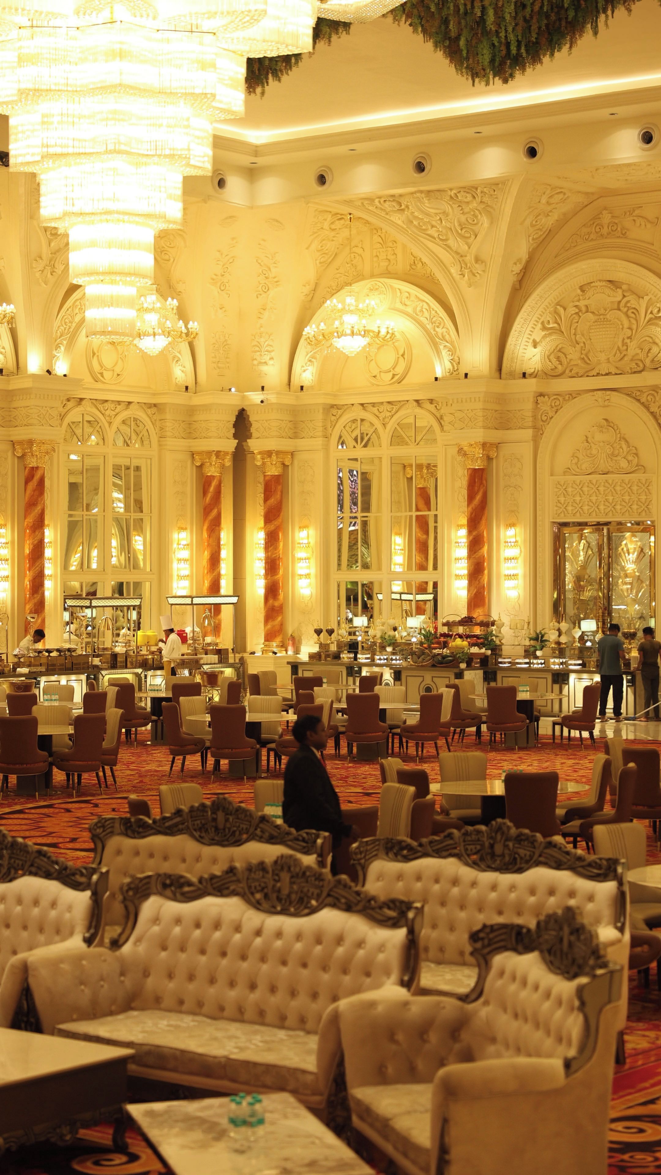 A grand hotel lobby with ornate chandeliers, large windows, and plush seating areas.