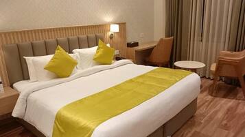 A hotel room with a large bed, two bedside tables, a desk, and a chair.