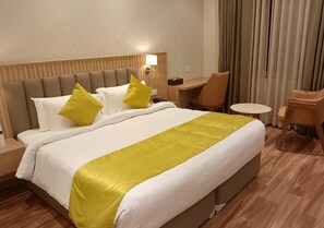 A hotel room with a large bed, two bedside tables, a desk, and a chair. - Antilia By Zion (Sonepat)