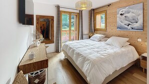 Un dormitorio con una cama grande, cabecera de madera, un espejo, cómoda, candelabro y un cuadro de osos polares.
