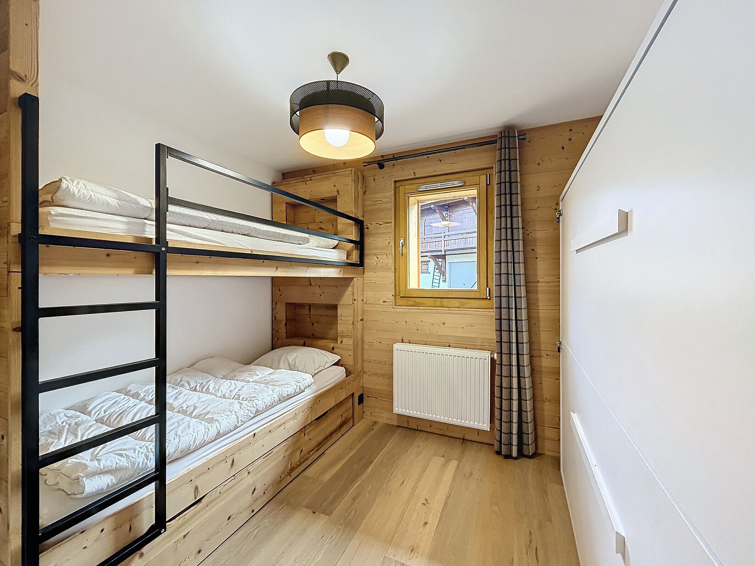 Habitació compacta amb lliteres, una finestra que ofereix vistes i un radiador.