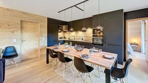 Una cocina moderna con armarios oscuros, encimeras de madera e iluminación colgante.